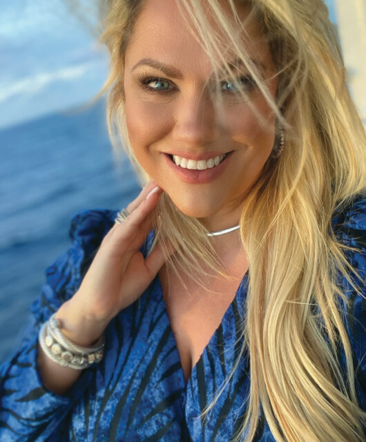 Headshot selfie of Christine Kestaloo wearing sterling silver jewelry on a cruise ship with the ocean behind her.