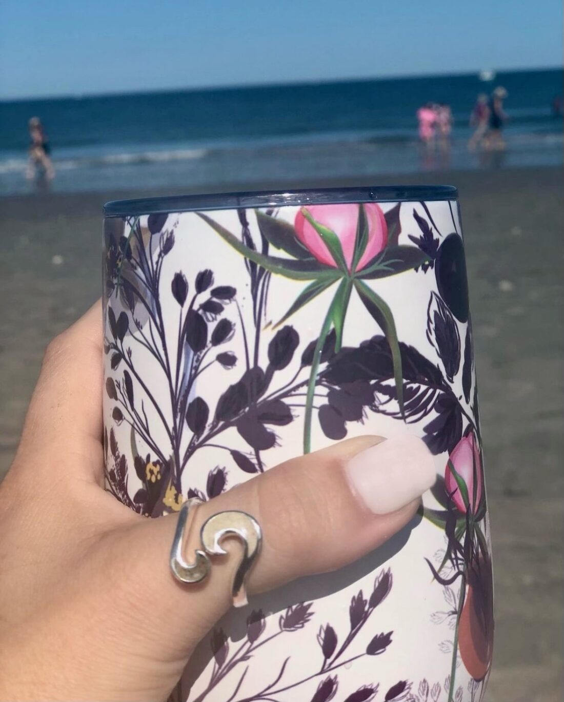 Hand holding mug and the person's thumb is wearing Dune Jewelry's Wave Bypass Ring, a sterling silver ring with two elements.