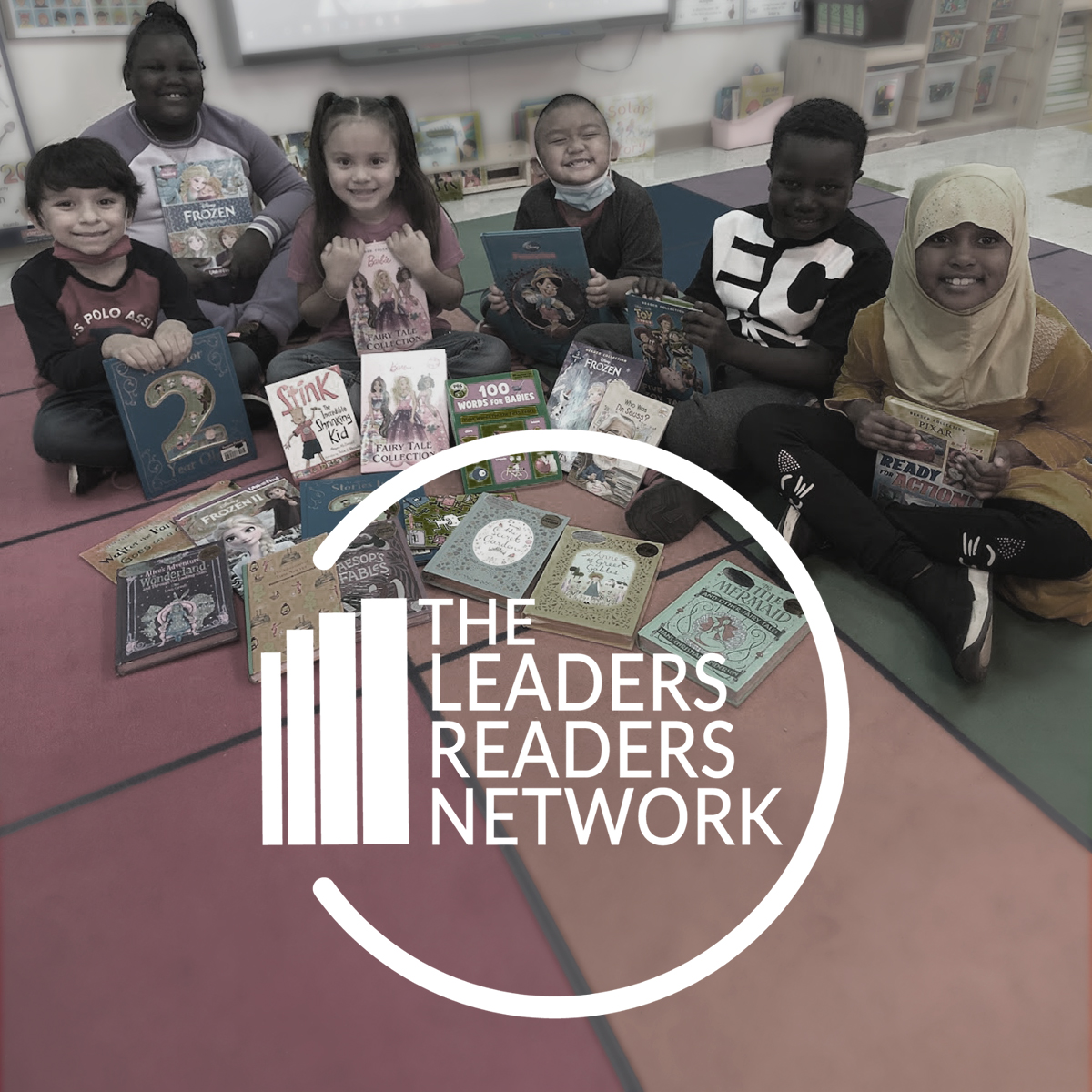 Photo of young kids gathered in half circle smiling at camera, with books. The Leaders Readers text is overlaid.