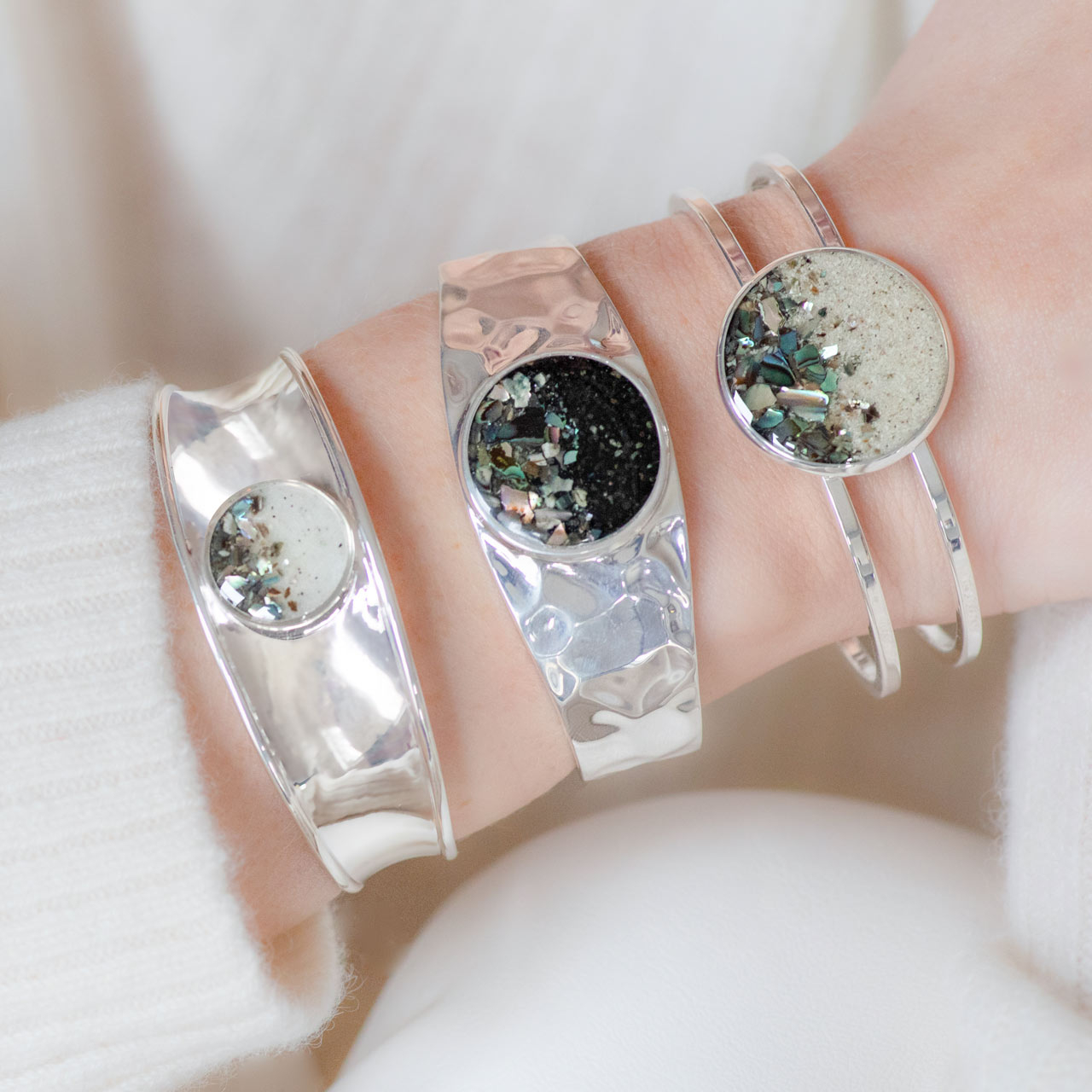 Product shot of wrist wearing three of Dune Jewelry's Abalone Gradient designs, including the Bayview Cuff Bracelet.