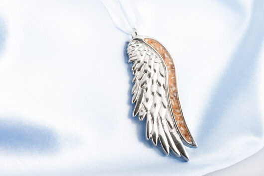 Angel wing ornament with ashes, shells, and rocks by Dune Jewelry