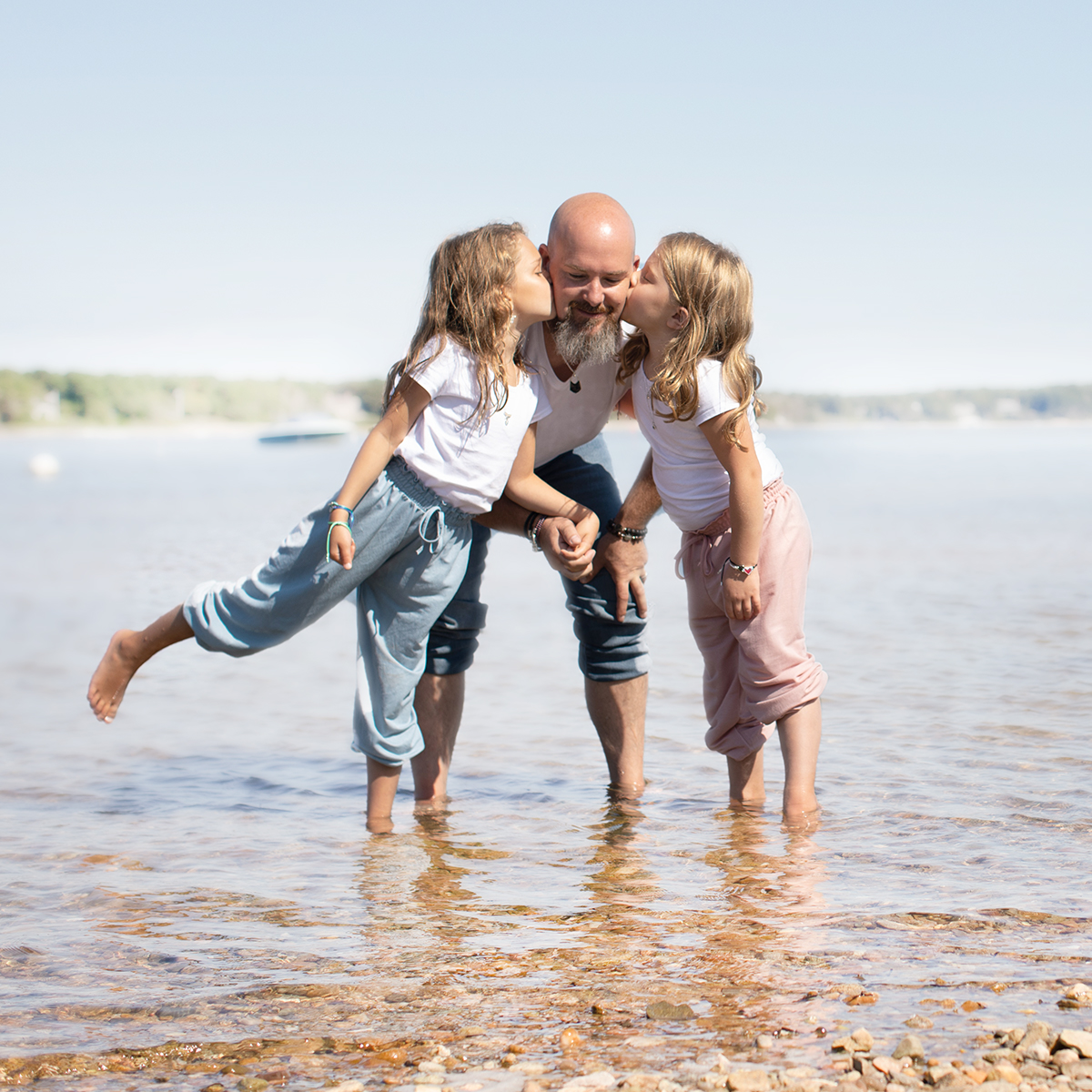 Holly Daniels Christensen's husband and two daughters with their feet in the water during low tide.