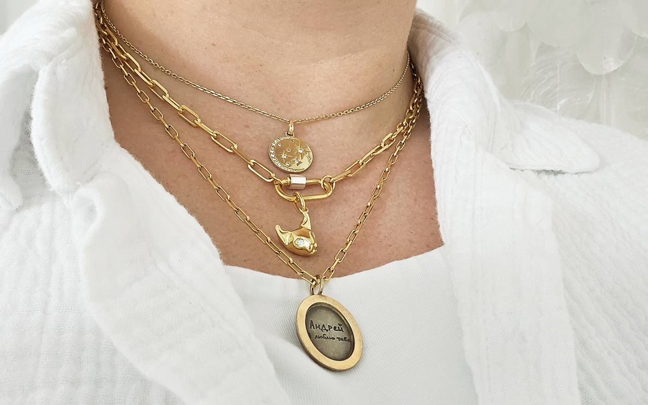 Gold paperclip chain and other chains featuring travel treasure charms.