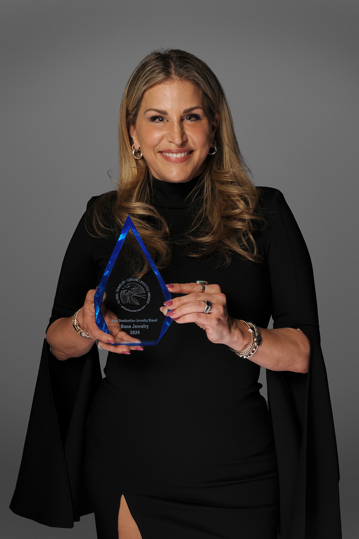 Holly Daniels Christensen of Dune Jewelry accepts the award from Best Vacation Jewelry Brand by Global Traveler Magazine on behalf of her brand.