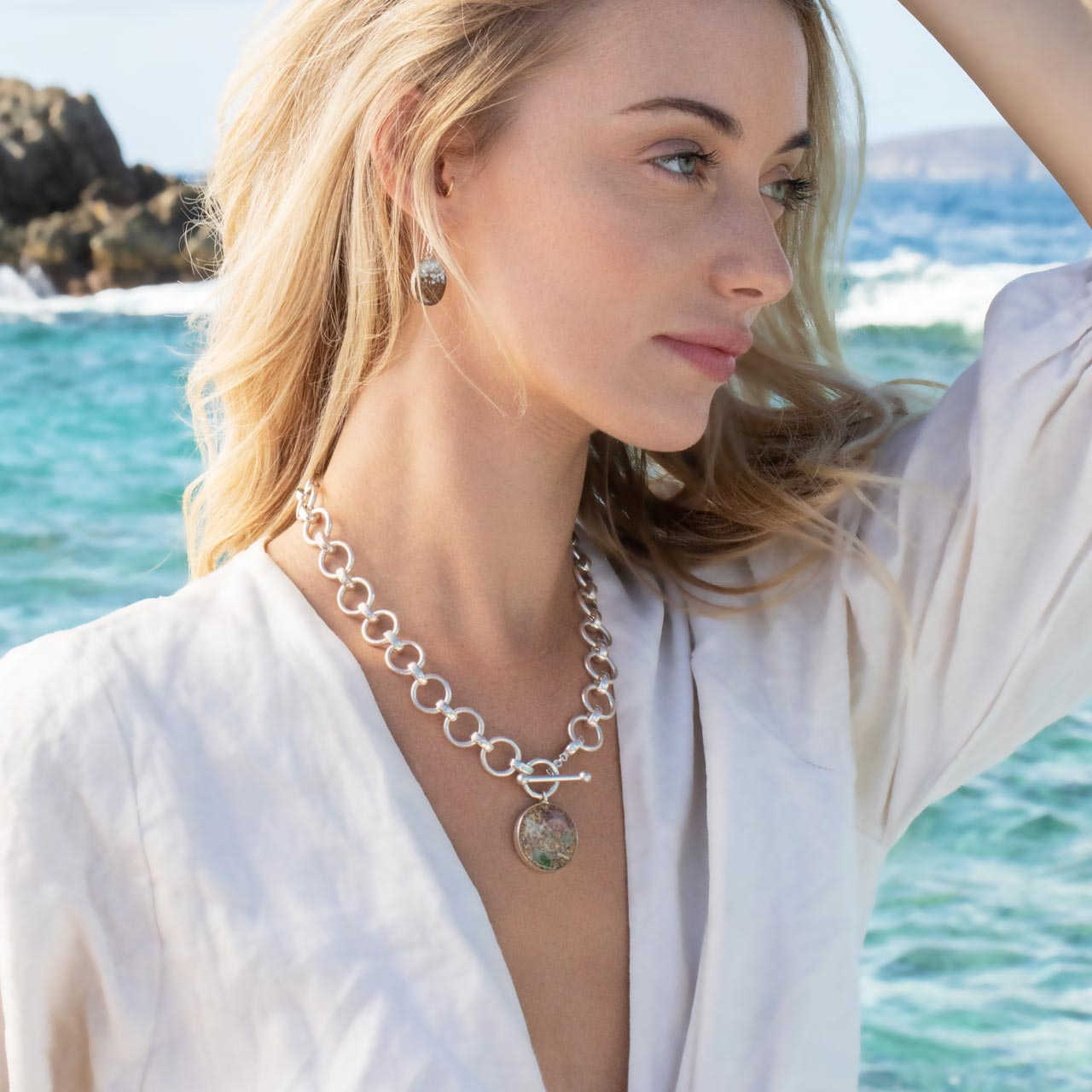 Mediterranean-inspired jewelry featuring a statement sterling silver chain and pendant with ethically sourced shells.