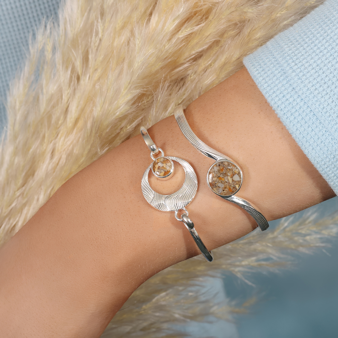 Sterling silver hinge bracelet with hooks and a circular wave textured bracelet charm with a small round sand setting.